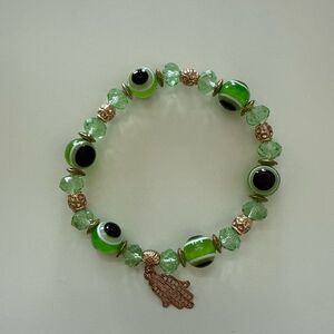 Green and gold tone evil eye beaded stretch bracelet with gold hamsa charm